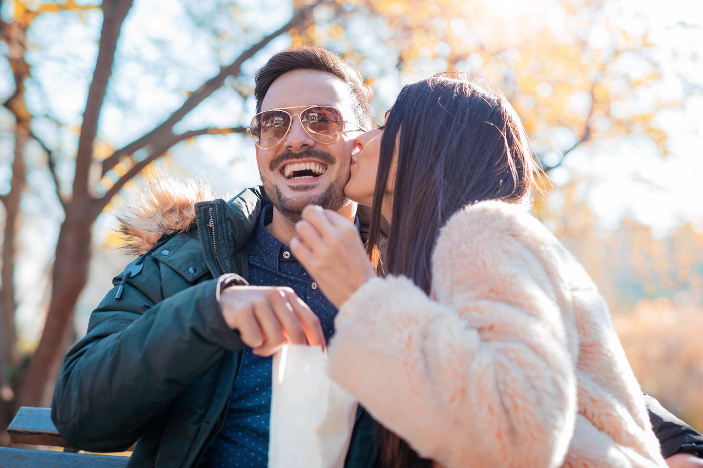 In einer Beziehung: Eine Frau küsst ihren lachenden Mann auf die Wange