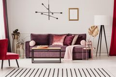 Wohntrend Modern Art déco: So kreierst du den edlen Style Wohntrend Modern Art déco: Lilafarbenes Samtsofa, daneben Tisch mit Deko
