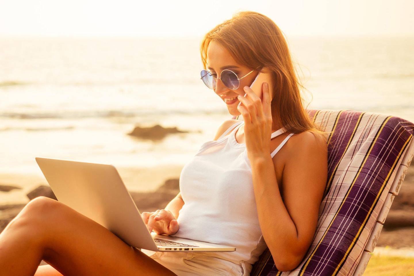 Bewerbung für einen Ferienjob: Frau arbeitet am Strand am PC