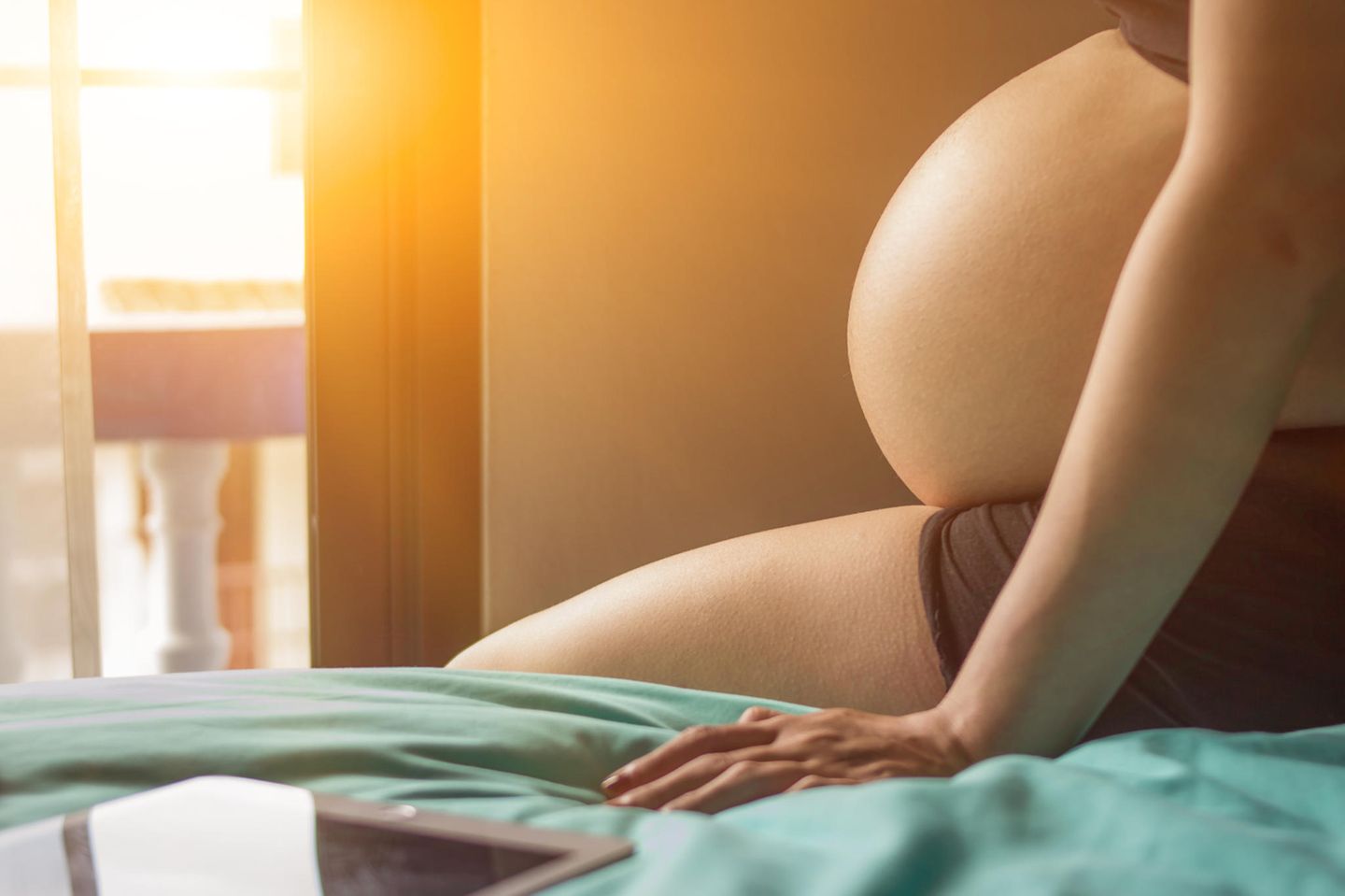 Klimawandel und Schwangerschaft: Schwangere sitzt auf Bett
