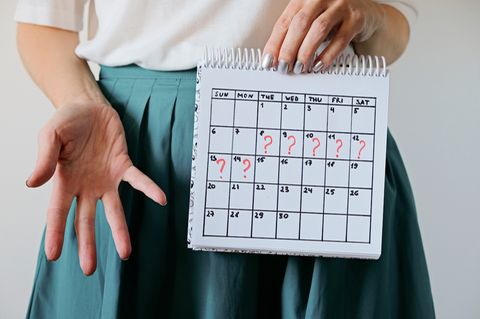 Tipps gegen verspätete Periode: Frau hält einen Kalender mit Fragezeichen