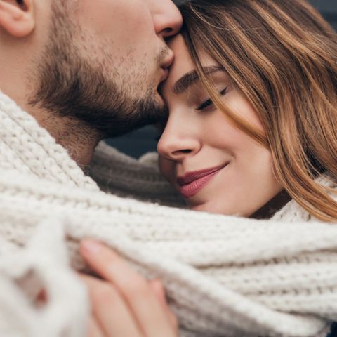 Kuss auf die Stirn: Mann küsst Freundin auf die Stirn