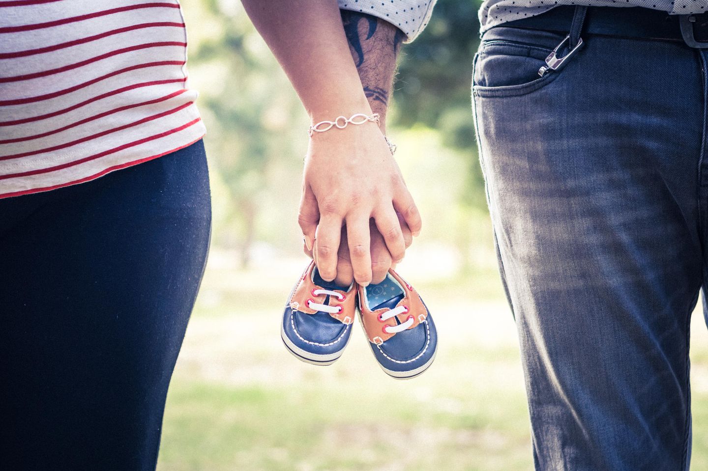 Schwangerschaft verkünden: Paar hält Babyschuhe in der Hand