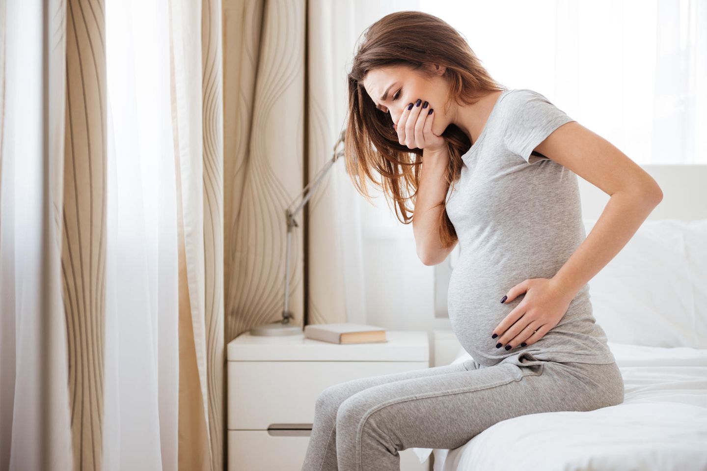 Schwangerschaftsübelkeit: Schwangere Frau hält sich die Hand vor den Mund