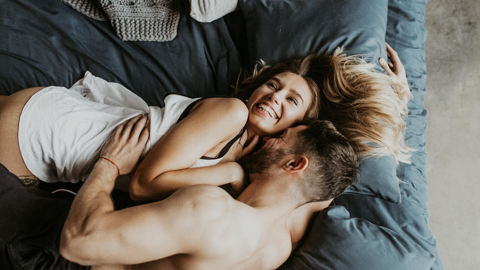 Mann küsst Frau den Nacken im Bett