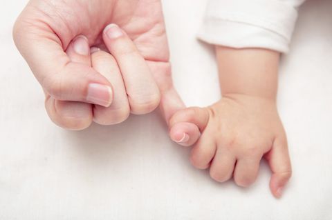 Baby hält kleinen Finger der Mutter