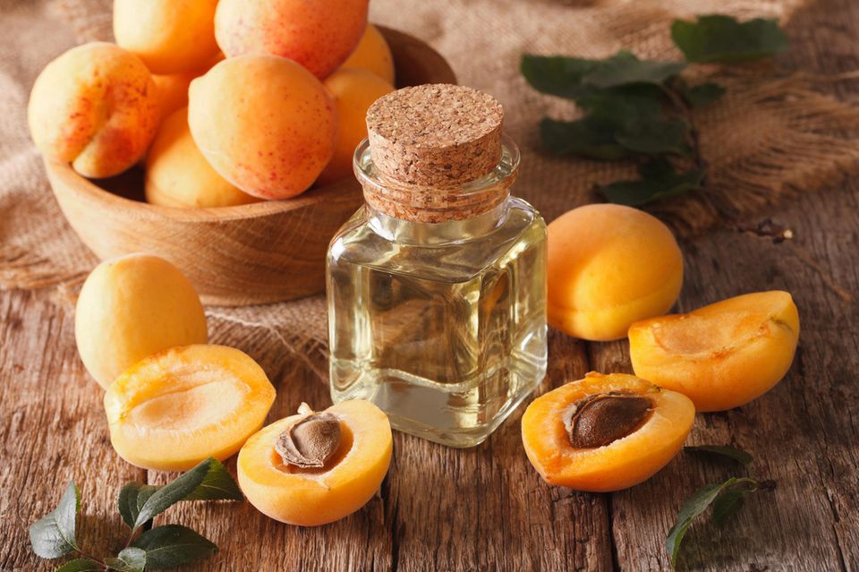Aprikosenkernöl: Kleine Flasche mit Öl und Aprikosen darum