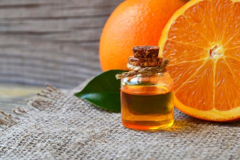 Orangenöl in der Flasche und Orangenhälften