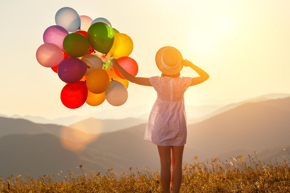 Horoskop: Eine Frau mit Luftballons auf einem Berg