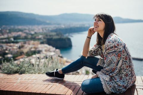 Tipps, wie du Geld sparst und glücklicher wirst: Eine glückliche Frau im Urlaub in Italien