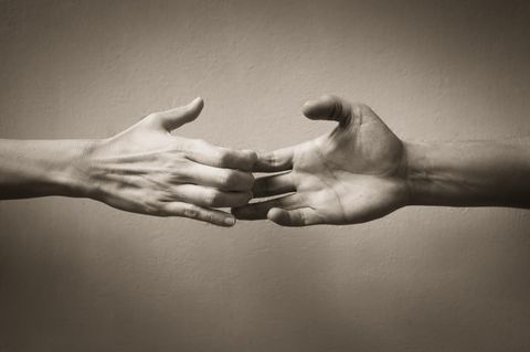Loslassen lernen: Zwei Hände in schwarz-weiß halten aneinander fest