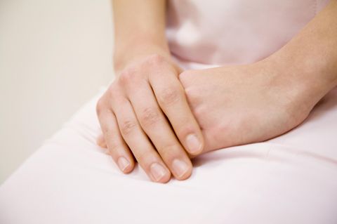 Lichen Sclerosus: Symptome der Hauterkrankung: Frau hält Hände verschränkt auf dem Schoß