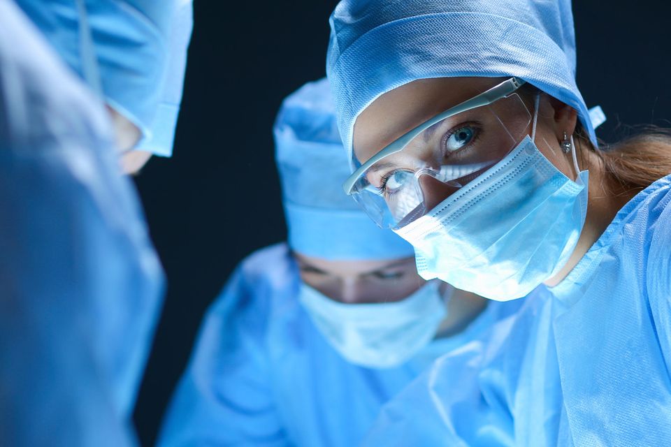 Eine Chirurgin trägt während ihrer Arbeit Mundschutz und OP-Kleidung