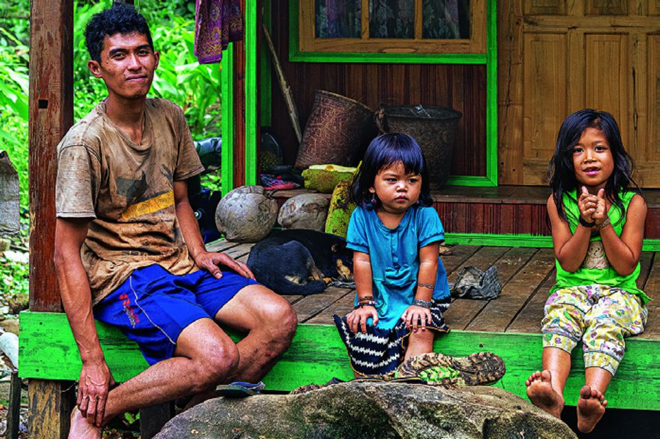 Reisetipps Borneo: Wie aus einer anderen Zeit: Mann und zwei kleine Kinder sitzen auf Veranda