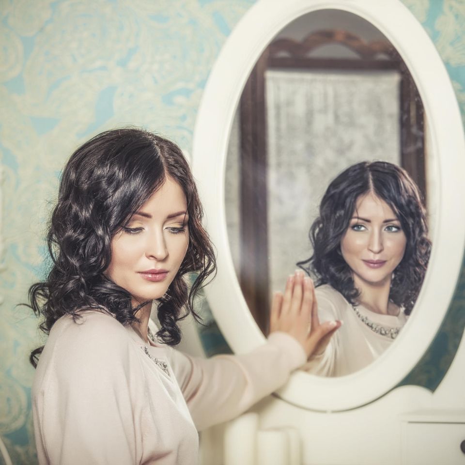 Frau mit Hand am Spiegel mit unterschiedlichem Spiegelbild