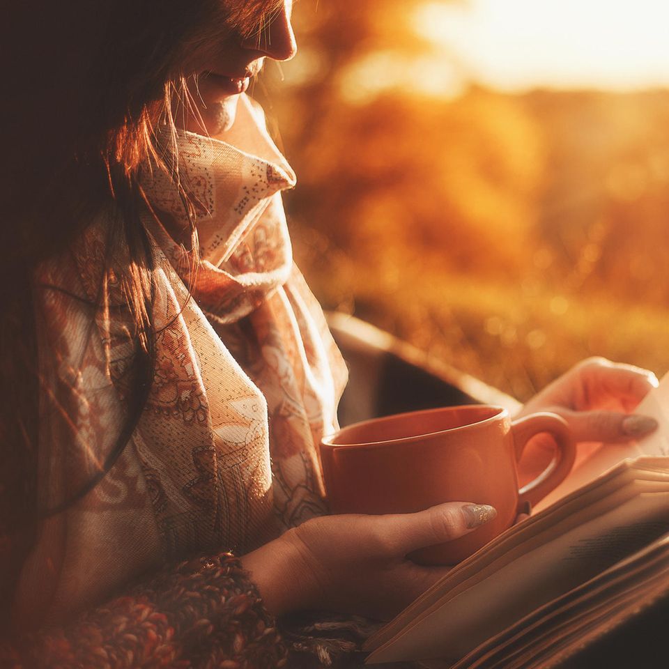 Frau liest Buch und trinkt Kaffee