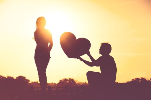 Horoskop: Ein Mann reicht einer Frau im Sonnenuntergang ein Herz