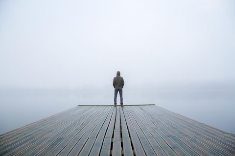 Mann auf Holzsteg bei Nebel