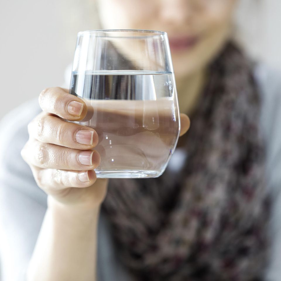 Frau hält ein Glas Wasser vor sich