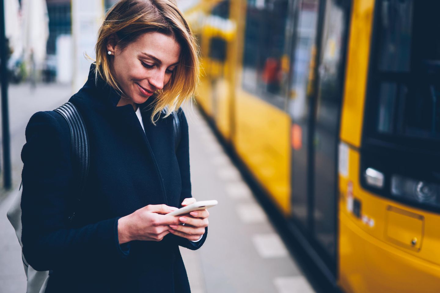 Nach dem ersten Date: Eine Frau schaut lächelnd auf ihr Handy