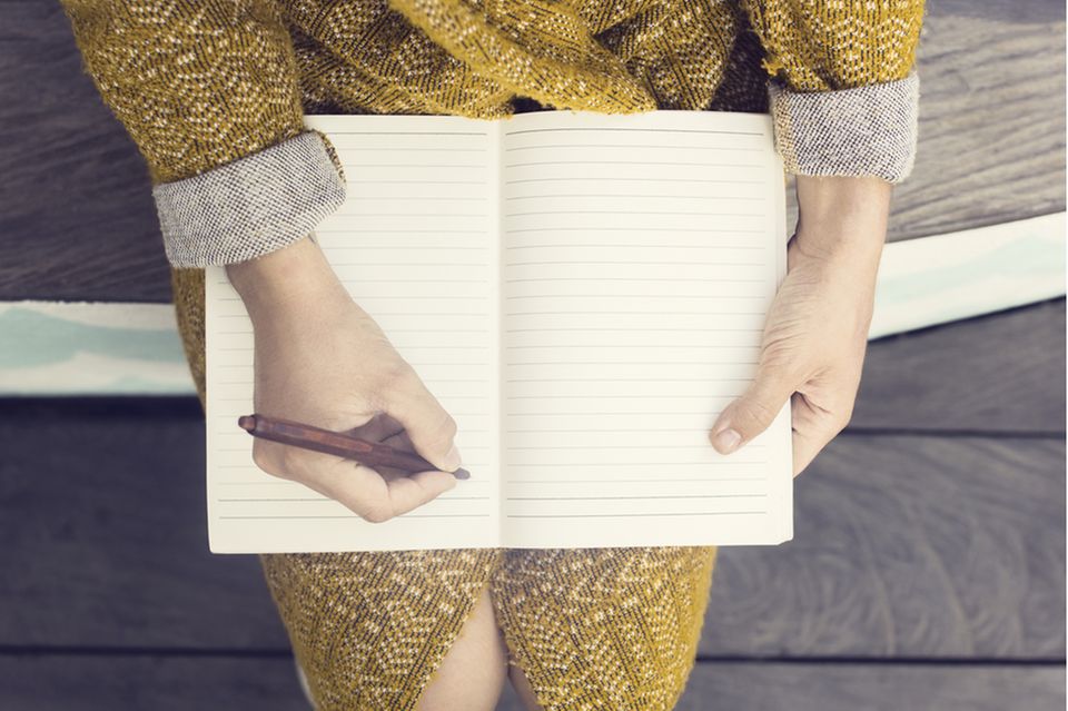 Dankbarkeitstagebuch: Frau mit Notizbuch auf dem Schoß