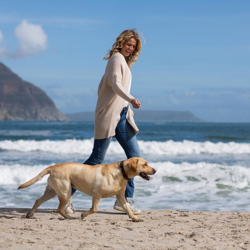 Wechseljahresbeschwerden lindern: Das hat geholfen: Frau mit Hund am Strand