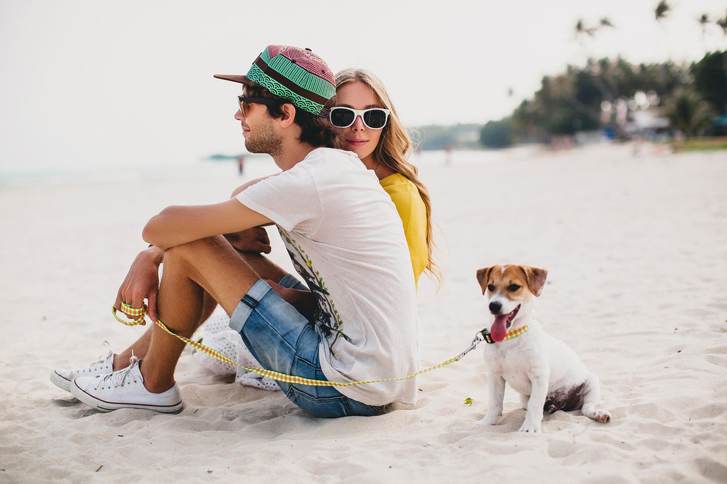 Date-Ideen: Ein stylisches Pärchen mit einem Hund am Strand