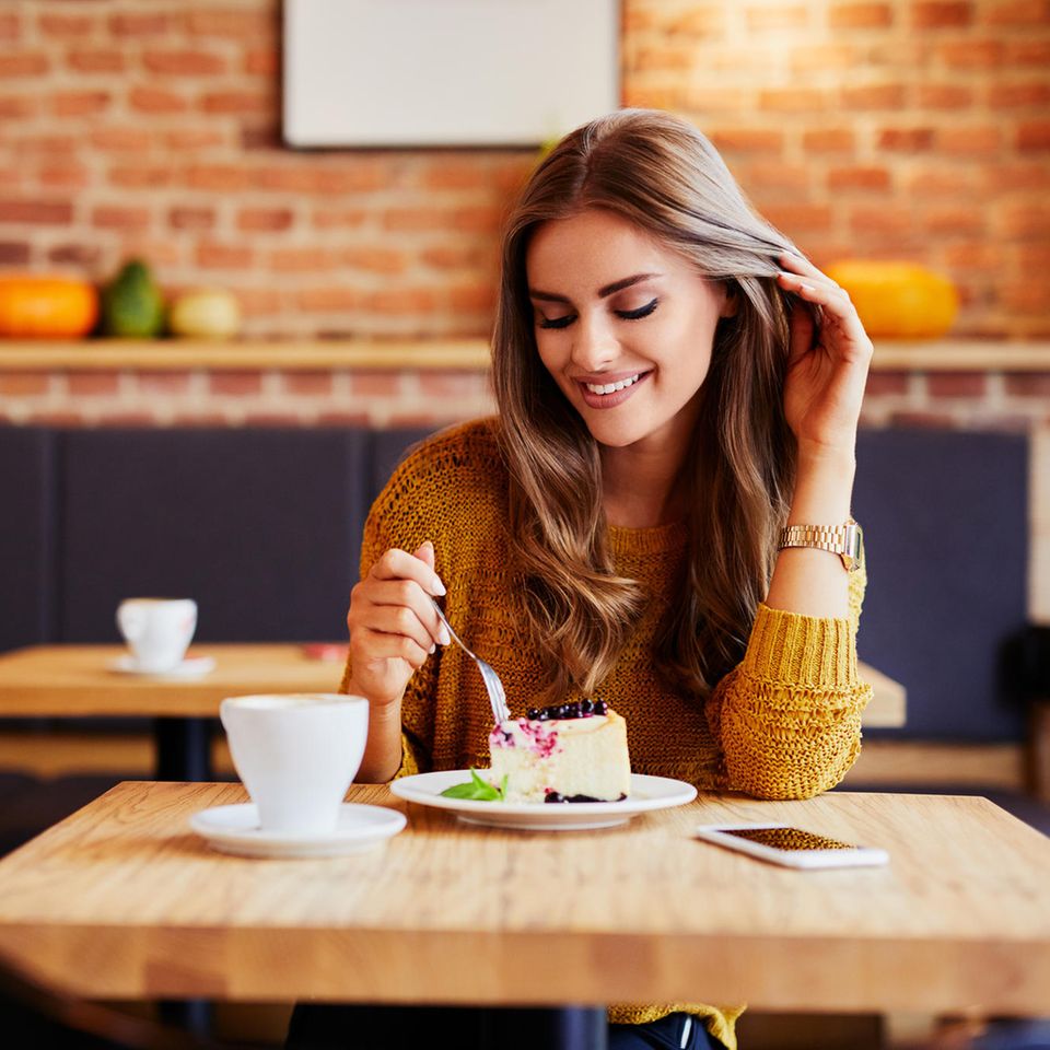 Frau im Cafe mit Kaffee und Kuchen