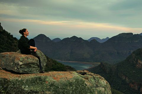 Drakensberge: Südafrika-Safari mal anders: Frau sitzt auf Stein vor bergiger Kulisse