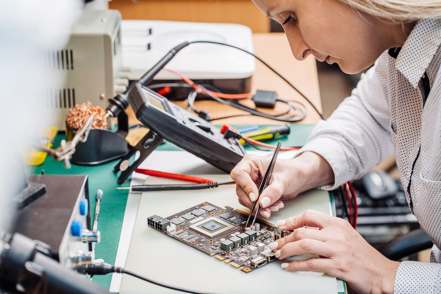 Elektrotechniker: Elektrotechnikerin arbeitet an einem Computerteil