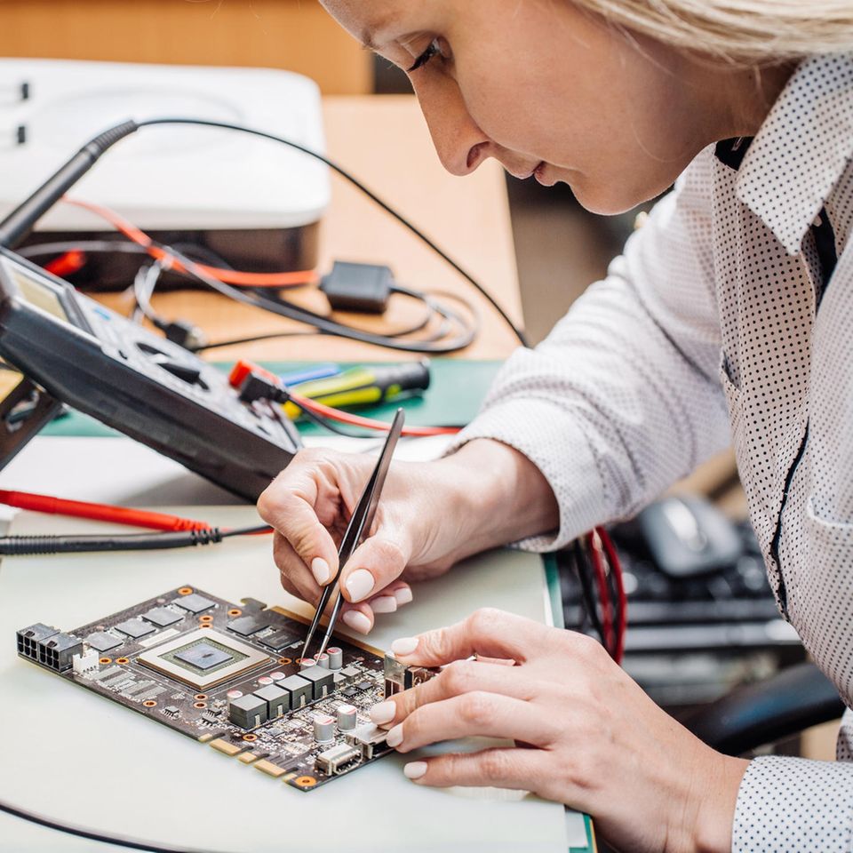 Elektrotechniker: Elektrotechnikerin arbeitet an einem Computerteil