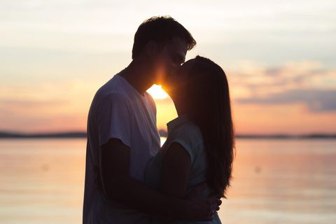Horoskop: Ein Pärchen küsst sich am Strand bei Sonnenuntergang