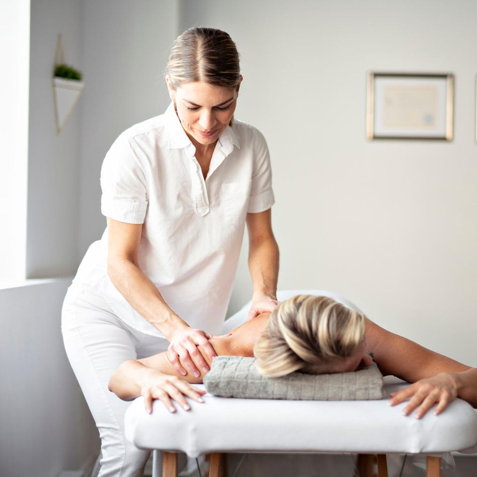 Masseur: Eine Masseurin behandelt den Rücken ihrer Patientin.