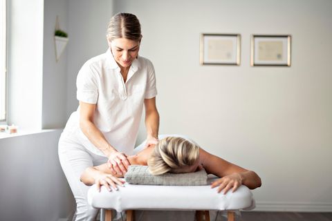 Masseur: Eine Masseurin behandelt den Rücken ihrer Patientin.