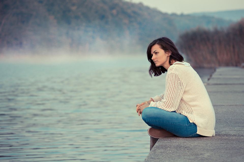 Schlechte Laune: Eine nachdenkliche Frau sitzt am See