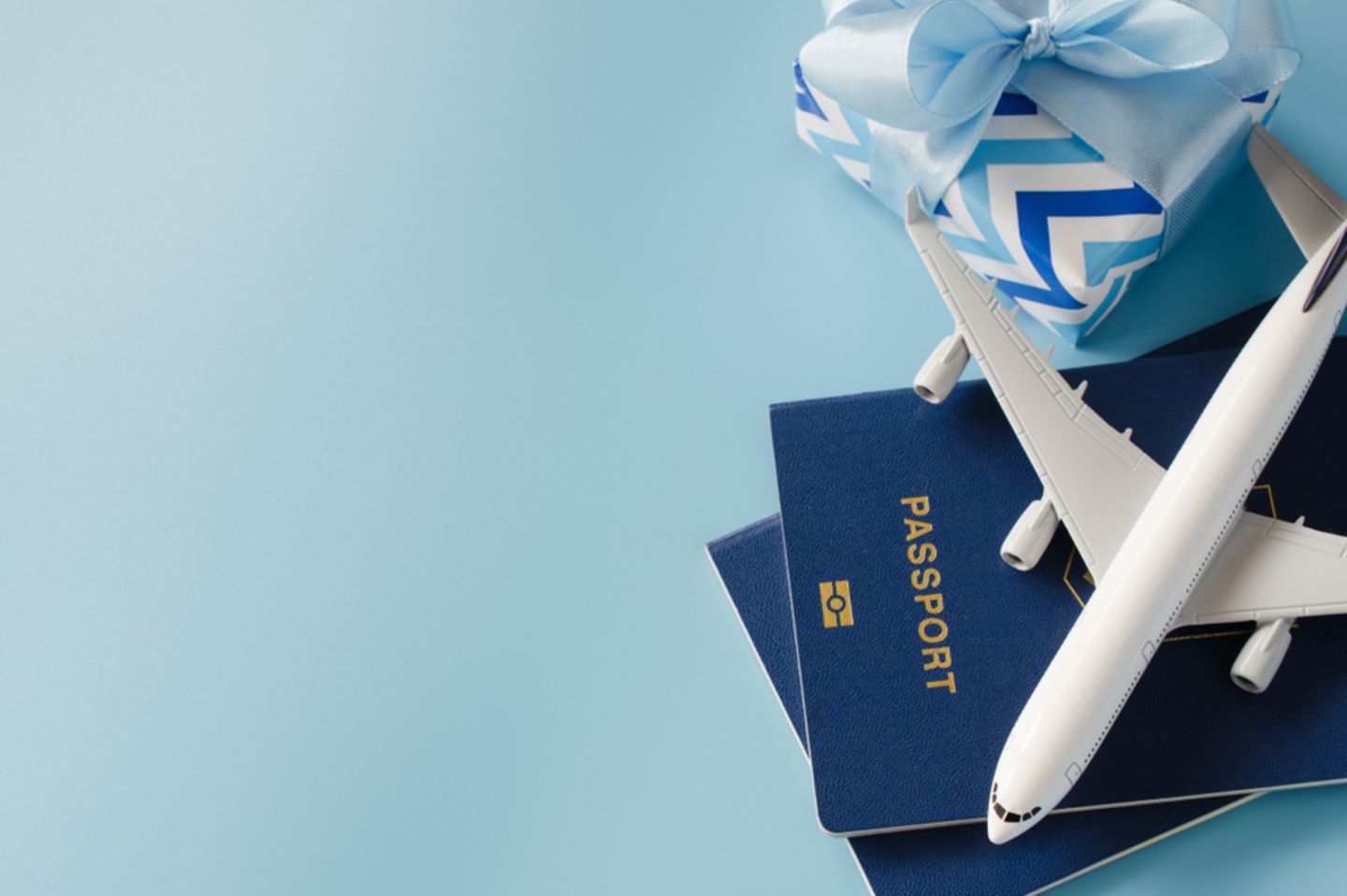 Reise-Geschenke: Modellflugzeug auf Reisepass, daneben ein Geschenk