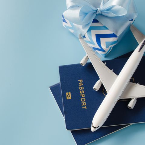 Reise-Geschenke: Modellflugzeug auf Reisepass, daneben ein Geschenk