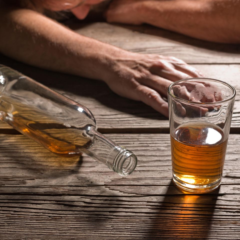 Brandyflasche und Glas vor betrunkenem Mann