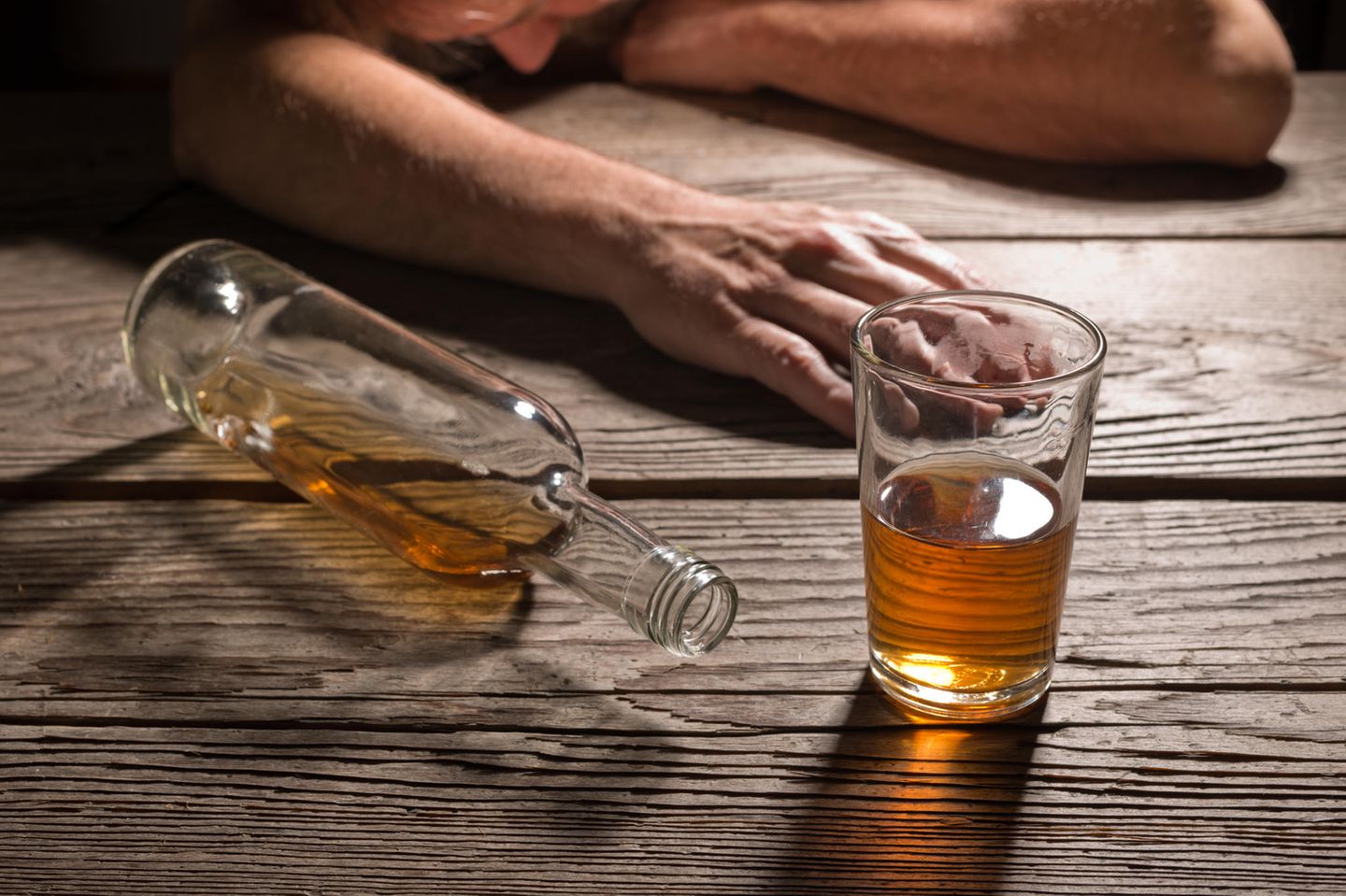 Brandyflasche und Glas vor betrunkenem Mann