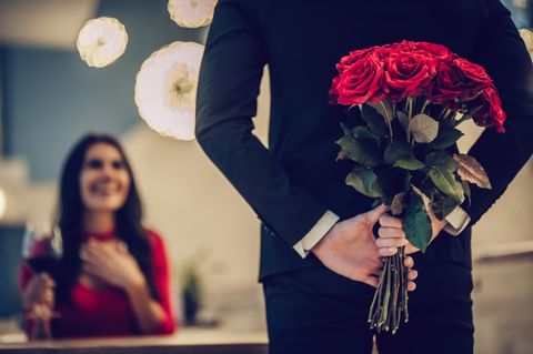 Horoskop: Ein Mann im Anzug mit einem Strauß Rosen hinterm Rücken