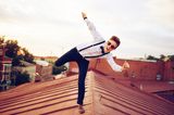 teambuilding-ideen: Junger Mann balanciert auf einem Dach