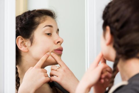 Aufgeschwollenes Gesicht: Frau kontrolliert unebene Stellen im Gesicht
