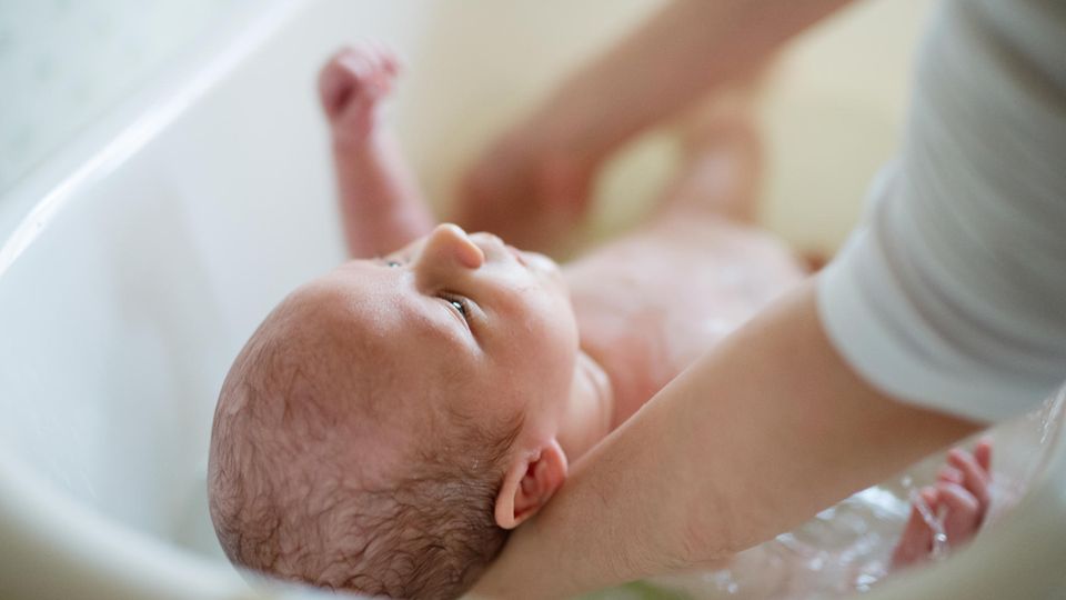 Hebamme badet Baby Babybad