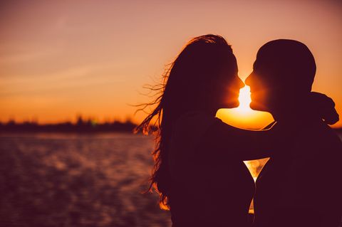 Wie viel Romantik braucht die Liebe?: Sich küssendes Paar vor Sonnenuntergang