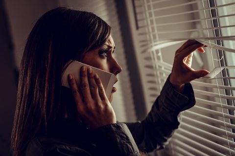 Blaues Wunder erleben: Frau am Handy schaut verschreckt aus Fenster
