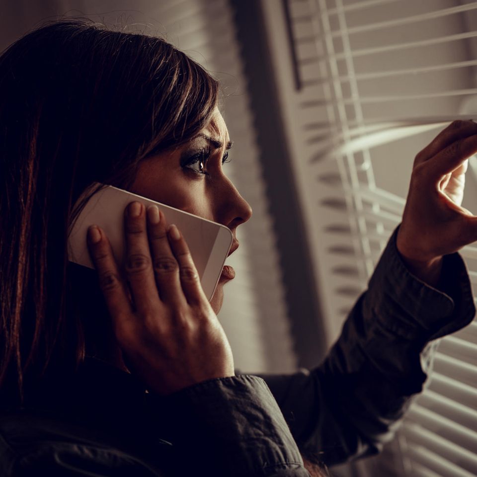 Blaues Wunder erleben: Frau am Handy schaut verschreckt aus Fenster