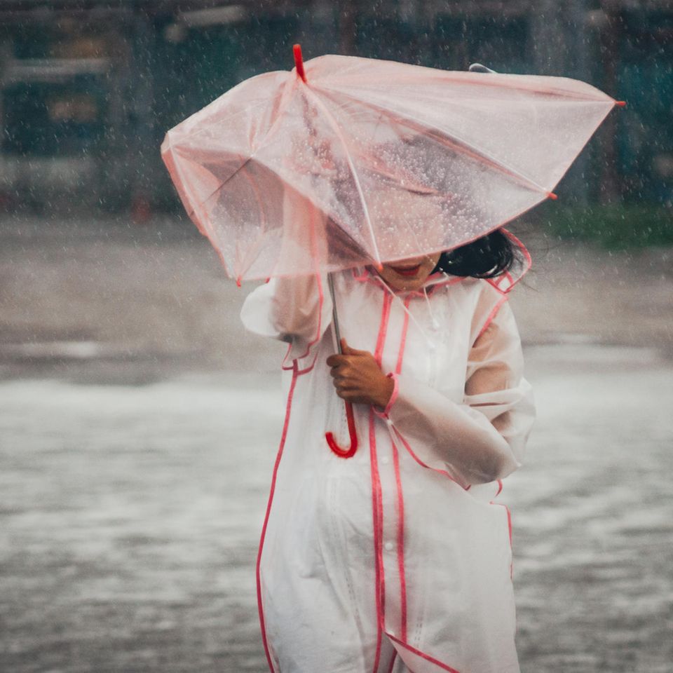 Vom Regen in die Traufe: Frau mit Regenschirm im Regen