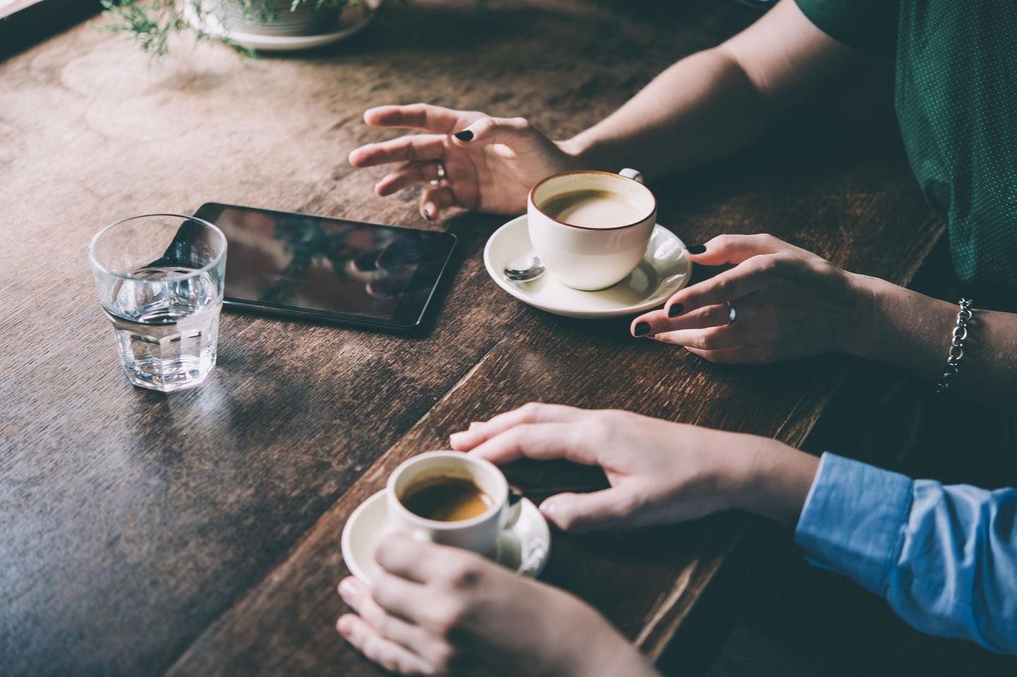 Mit gestressten Menschen reden: Zwei Menschen sitzen am Tisch und trinken Kaffee