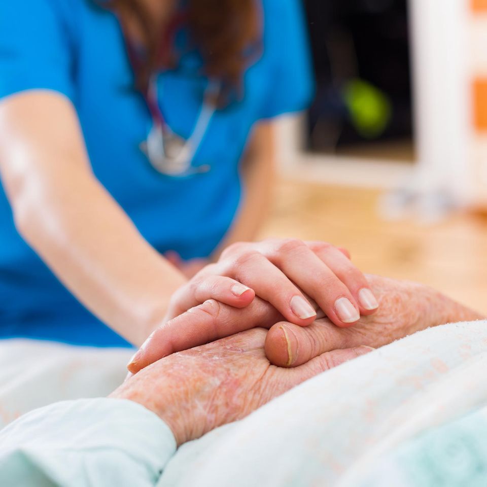 Seniorin im Krankenbett Pflegerin hält ihre Hand