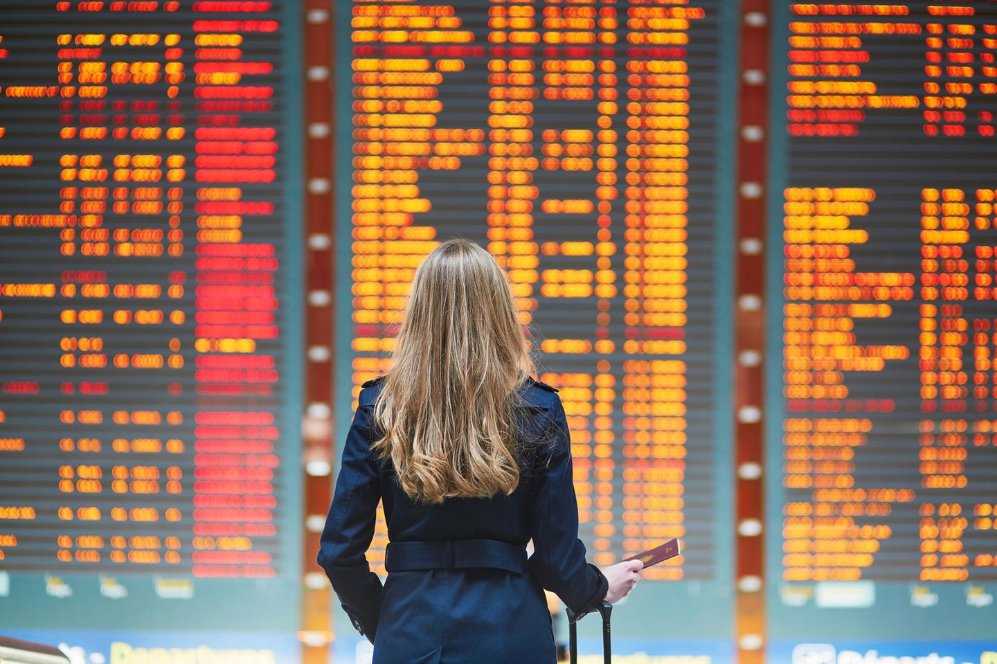 Reise stornieren: Frau vor den Flugplänen am Flughafen